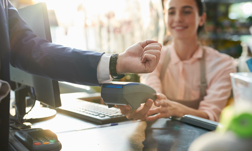 A business person tapping wrist watch on eftpos machine