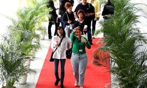 Team of people walking into an event with lots of live trees and a red carpet