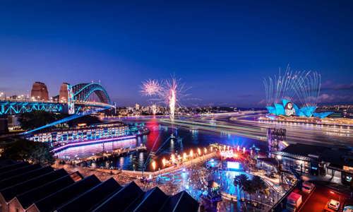 Fireworks above Sydney Harbour during Vivid 2024 with lights illuminating the bridge, Opera House and Watersedge