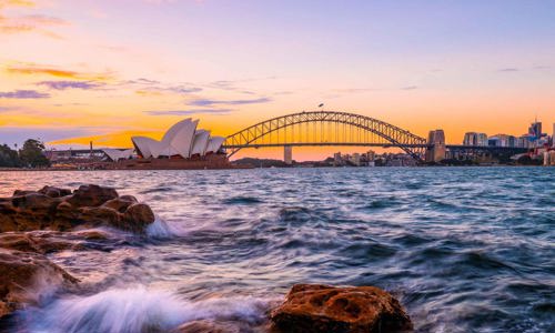 water over rocks with Harbour Bridge and Opera House in distance