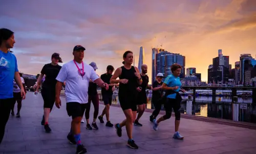 city walks with group of people running near the harbour at sunrise