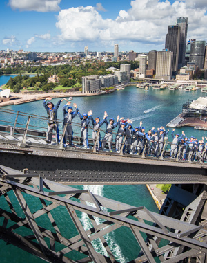 Row of climbers smiling during the Bridge Climb Tour with Sydney cityscape in background